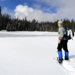 Snowshoer approaching frozen Deer Lake e1544034156615